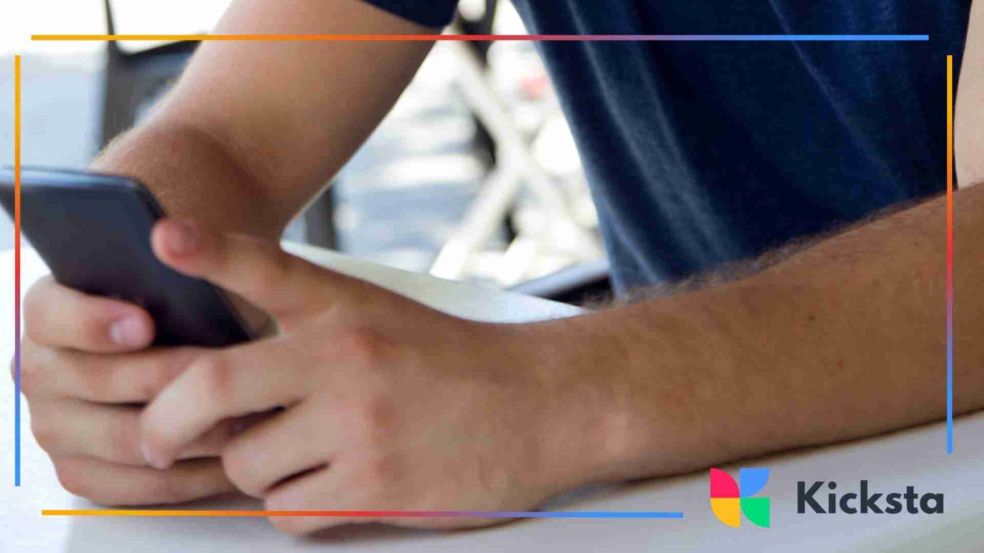 Close-up of a person holding a smartphone with both hands while sitting outdoors.