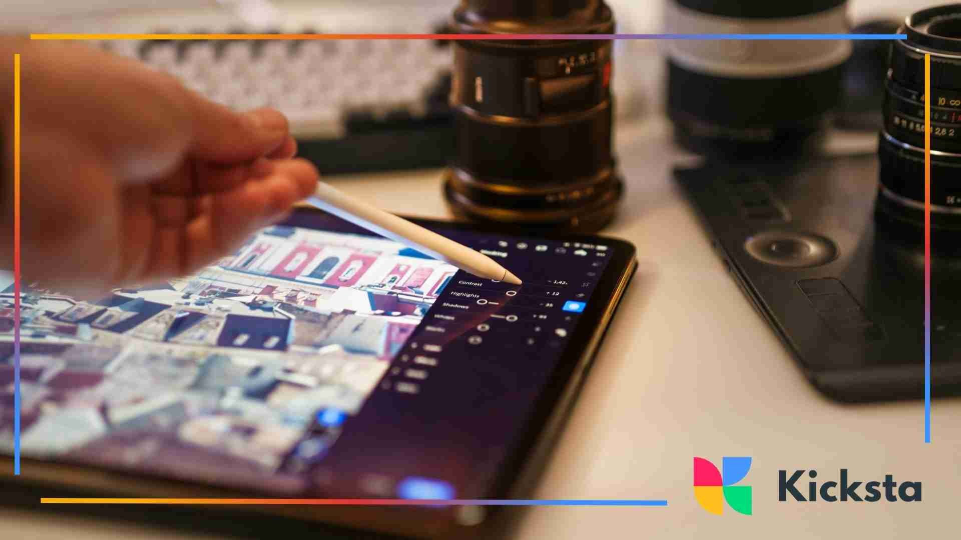 Person using a stylus to edit images on a tablet surrounded by camera lenses and gear.