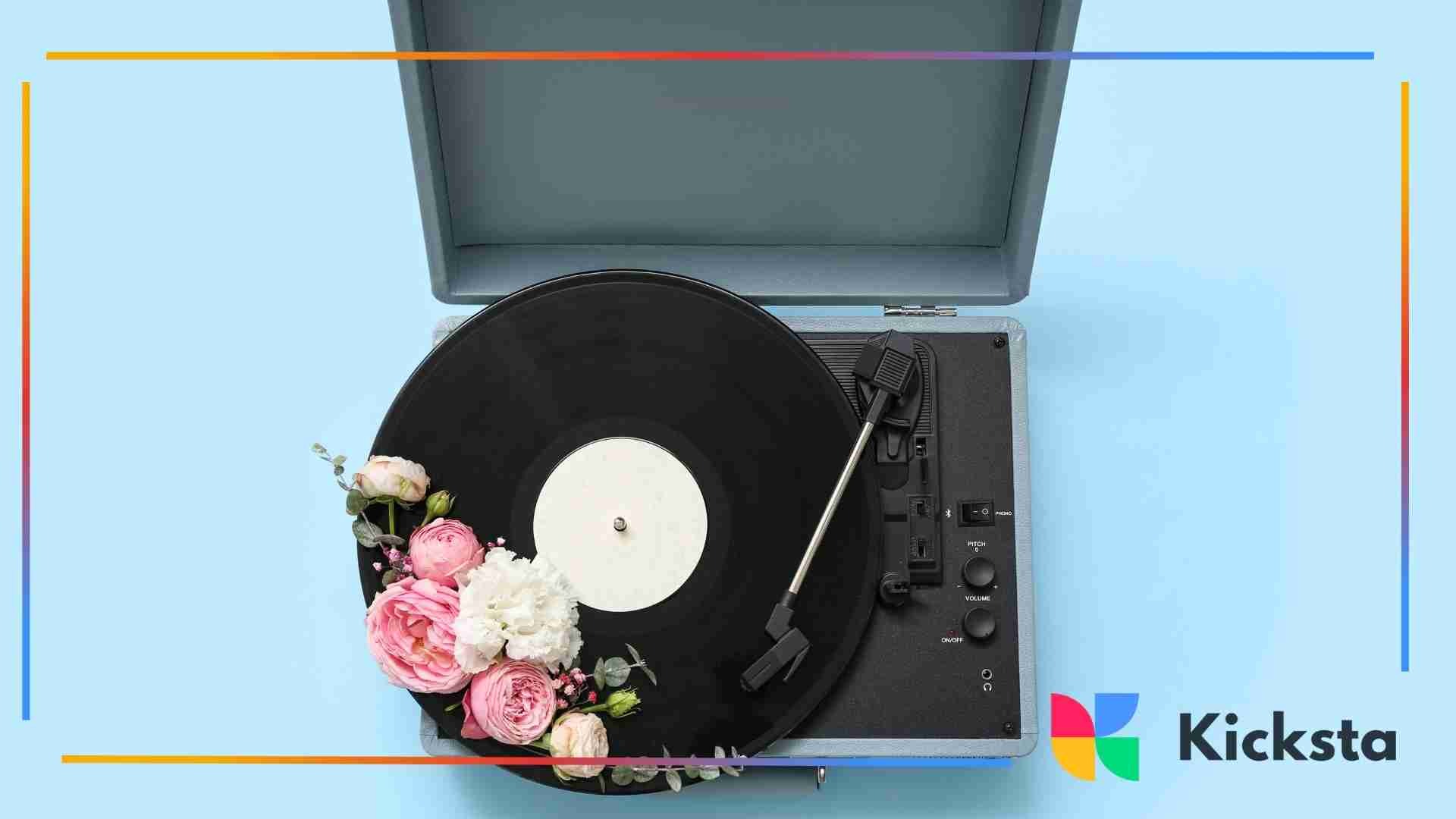 Close-up of a vinyl record player decorated with pink and white flowers on a light blue background.
