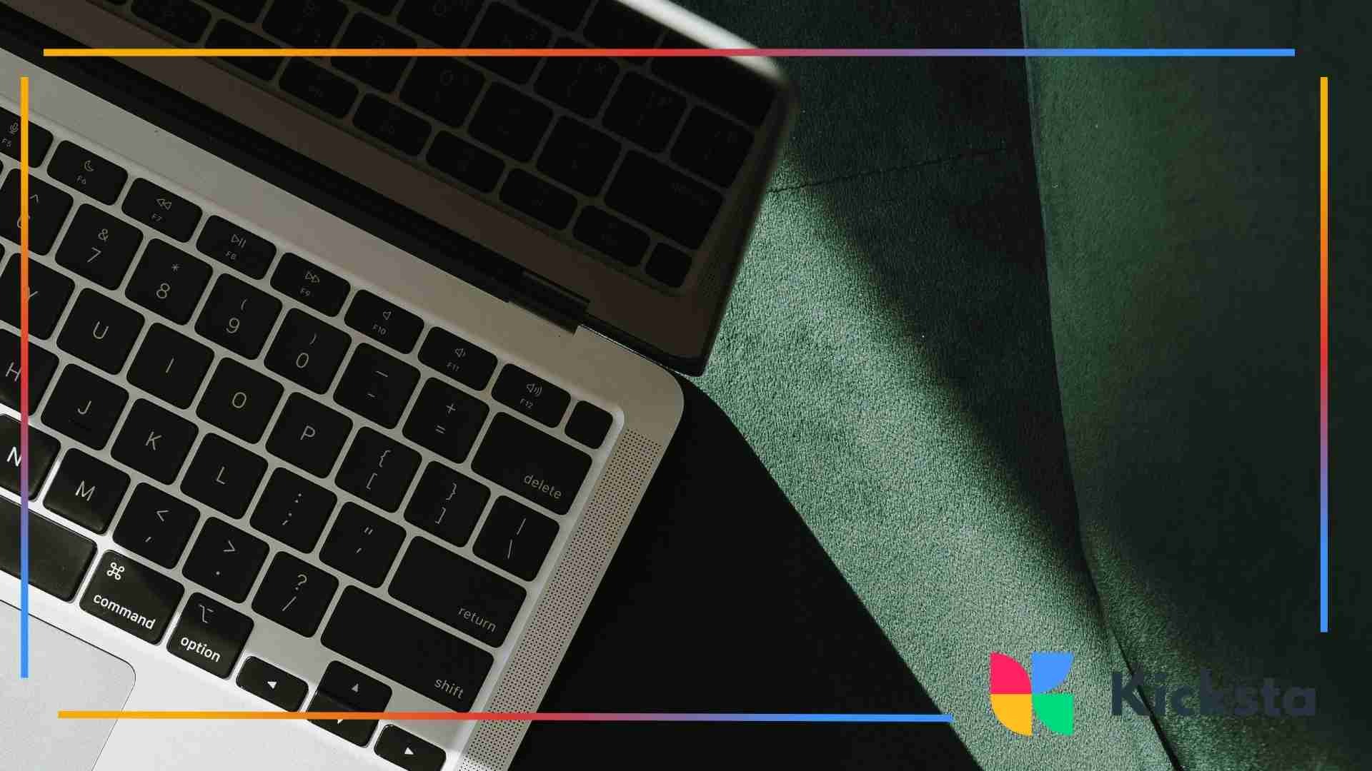 Close-up of a laptop keyboard with strong sunlight casting shadows across the keys and a green surface beside it.