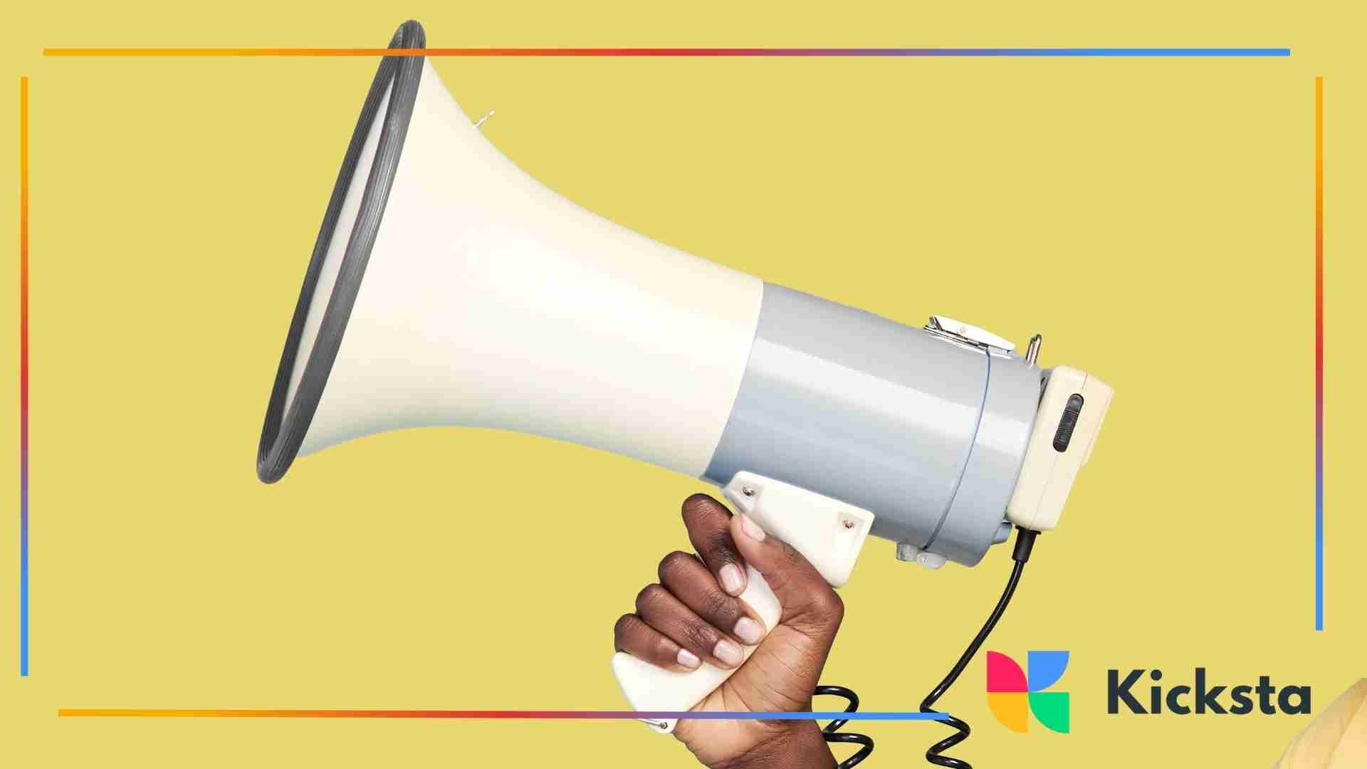 Hand holding a megaphone against a yellow background, symbolizing announcement or promotion