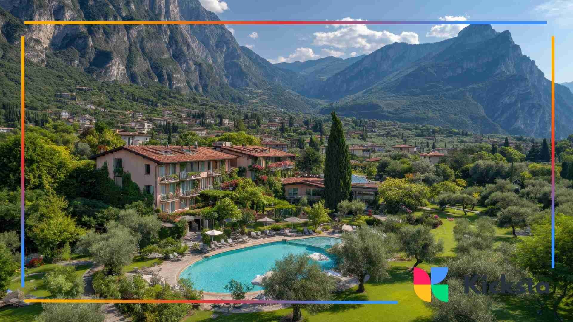 A scenic mountain resort surrounded by lush greenery, featuring a turquoise swimming pool and alpine peaks in the background.