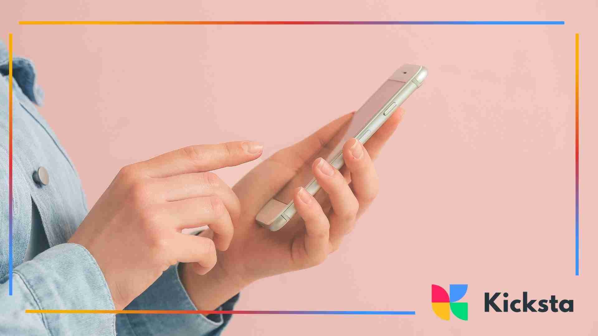 Hands holding a smartphone against a pink background, with one finger tapping the screen.