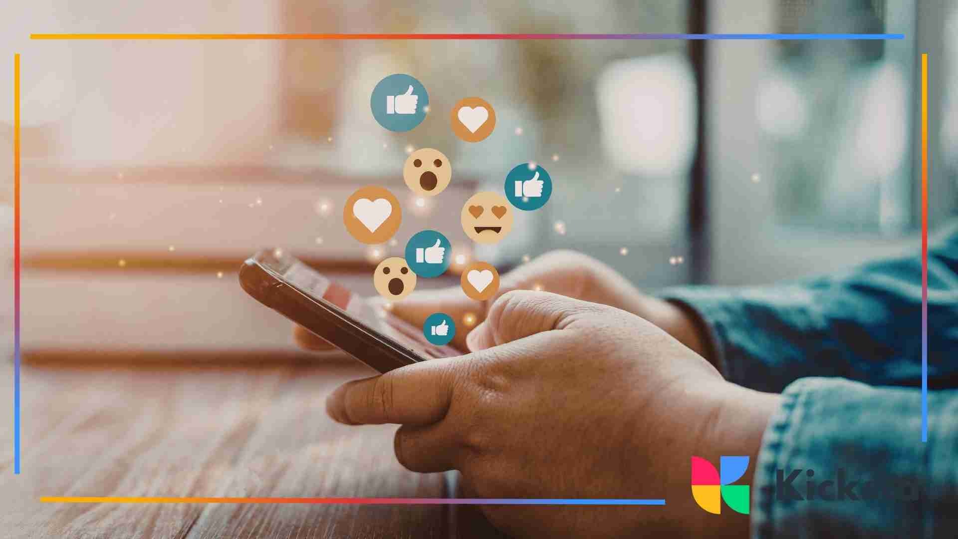 Hands holding a smartphone while social media reaction icons like hearts, likes, and emojis float above the screen.