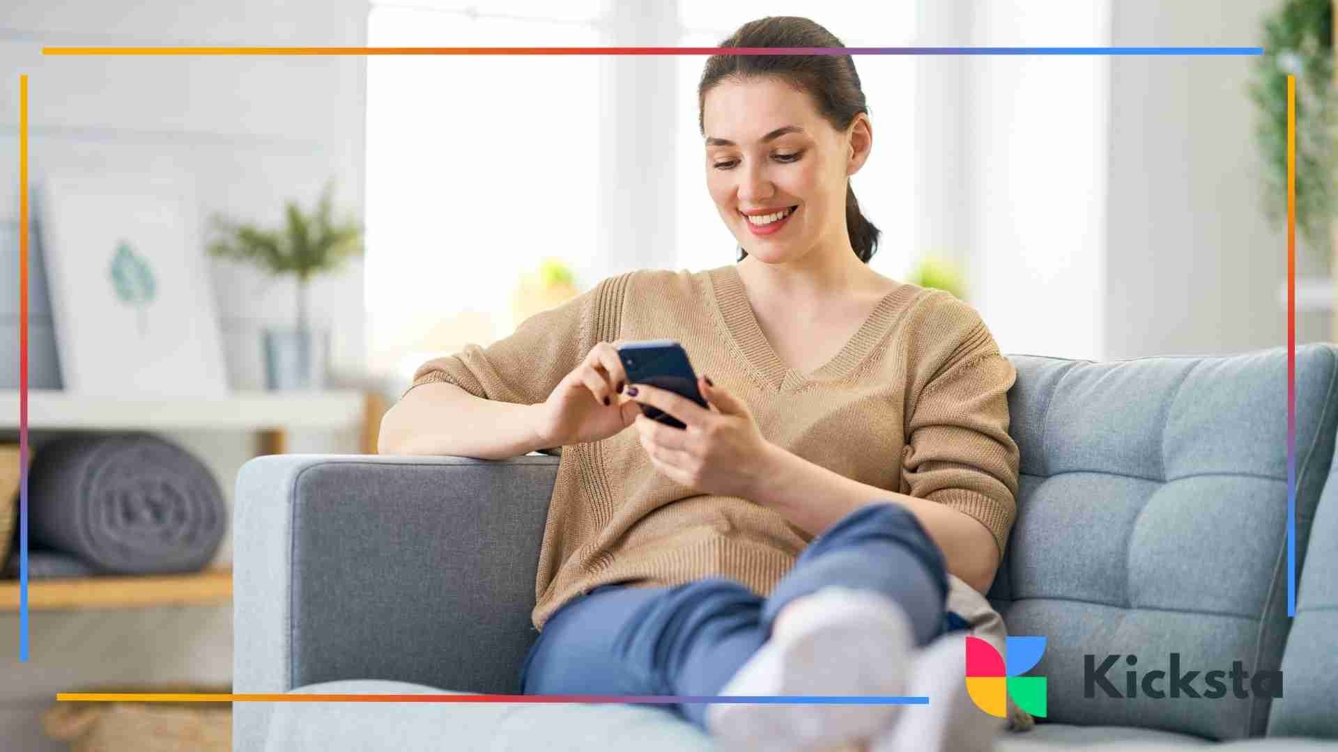 Woman relaxing on a sofa and smiling while using her smartphone.