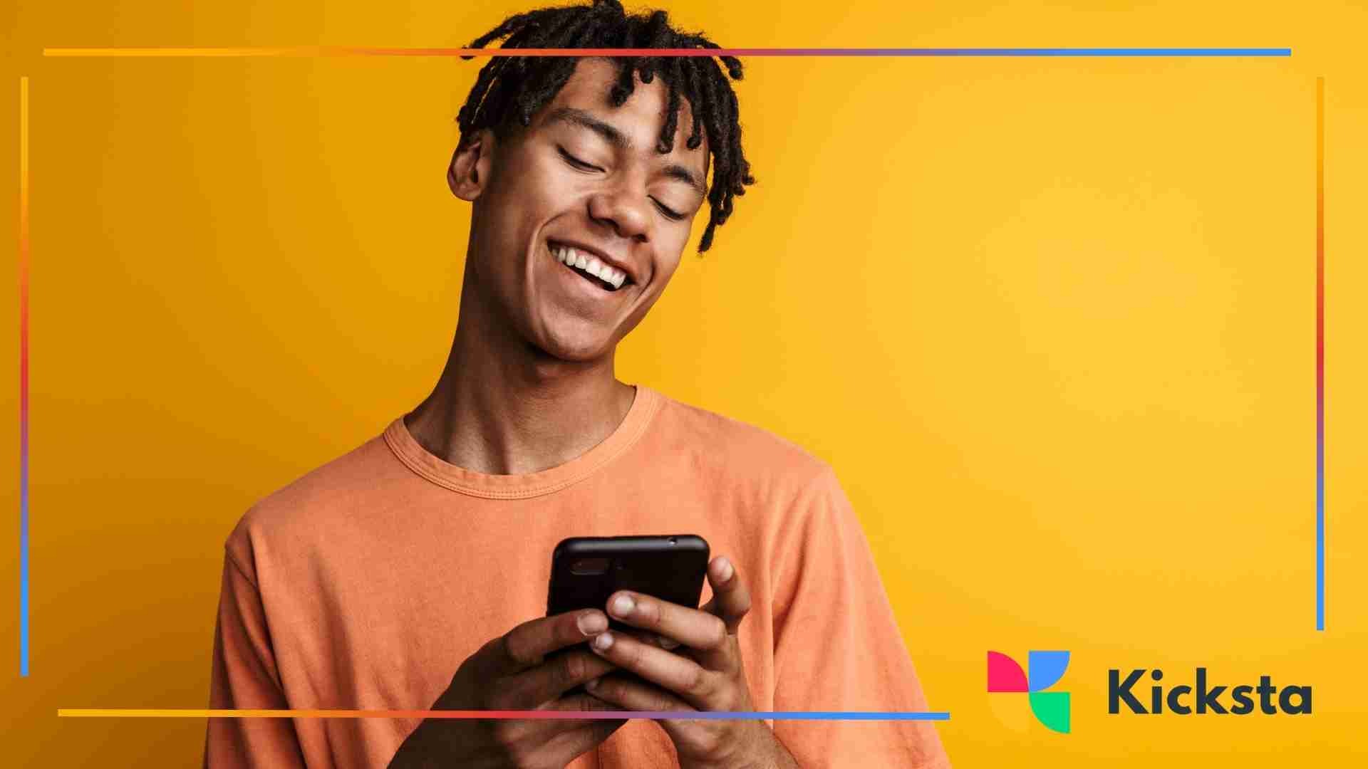Person smiling while looking at a smartphone against a yellow background.