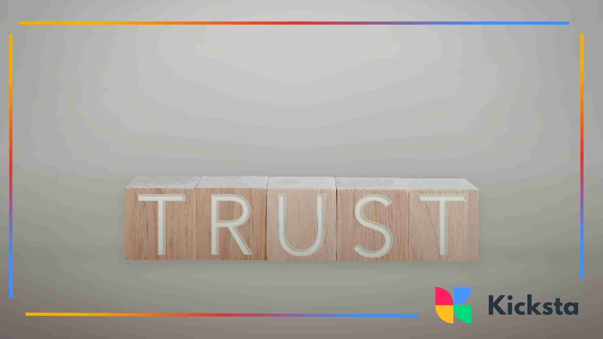 Wooden blocks arranged to spell the word “trust” on a neutral background.