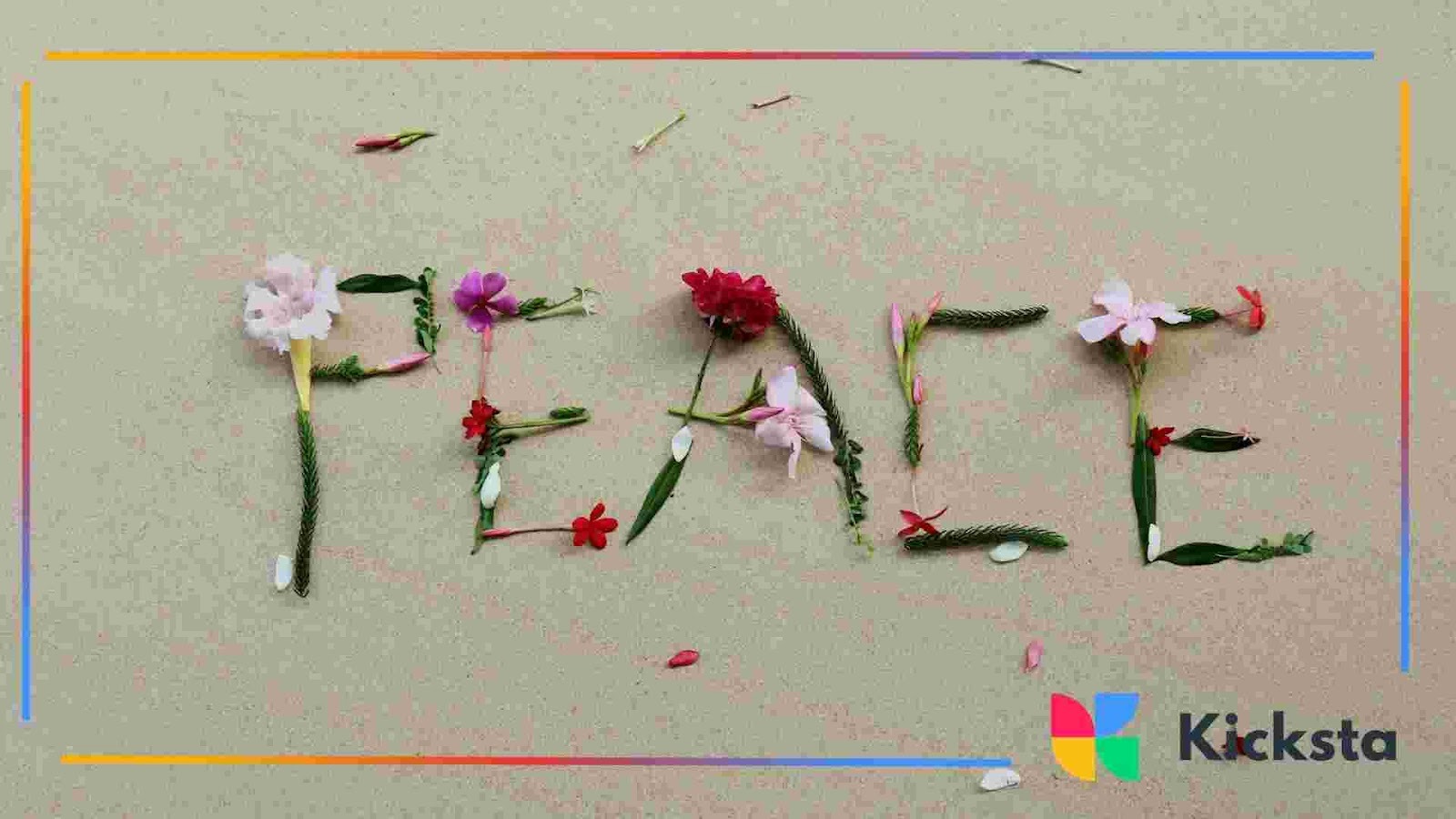 The word “peace” spelled out using flowers, leaves, and small plants on sand.