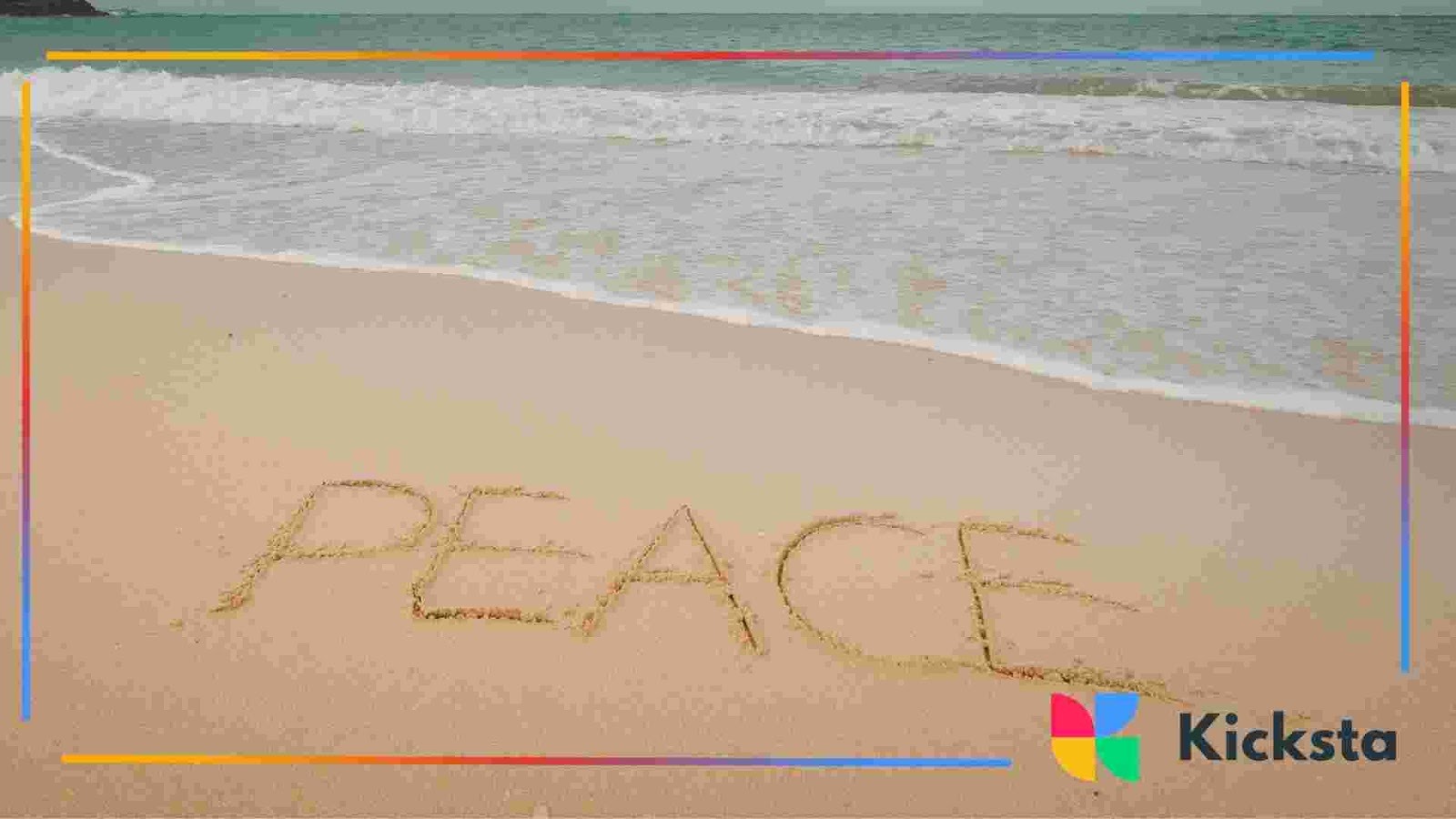The word “peace” written in sand near the shoreline with ocean waves in the background.