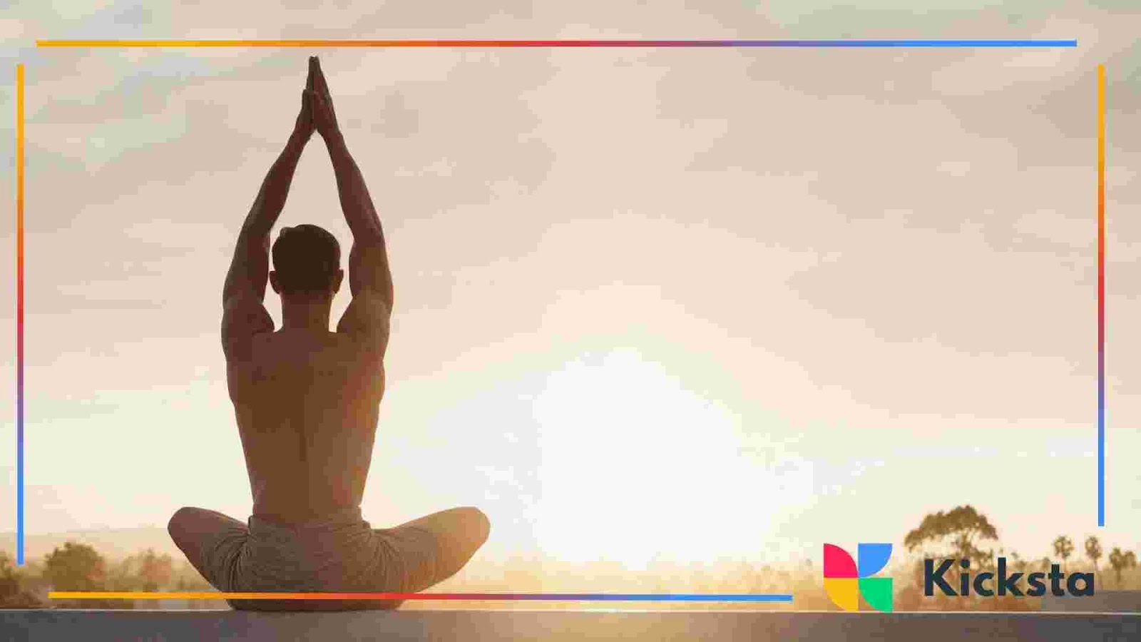 Person sitting cross-legged with hands raised overhead during sunrise in an outdoor setting.