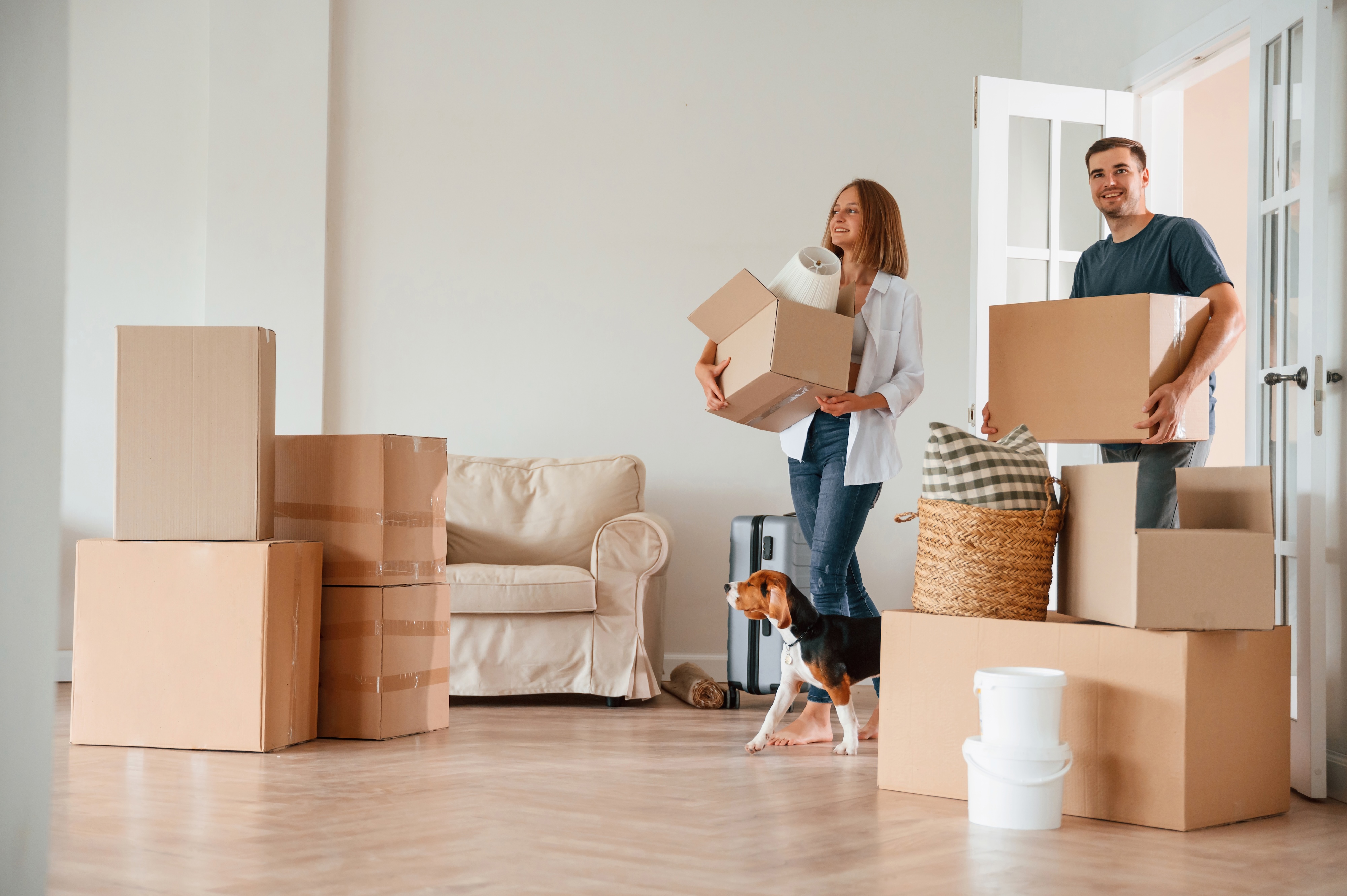 Happy couple carrying moving boxes into their new apartment with their dog, depicting the excitement of moving into Views at The Peak Apartments in Phoenix, AZ