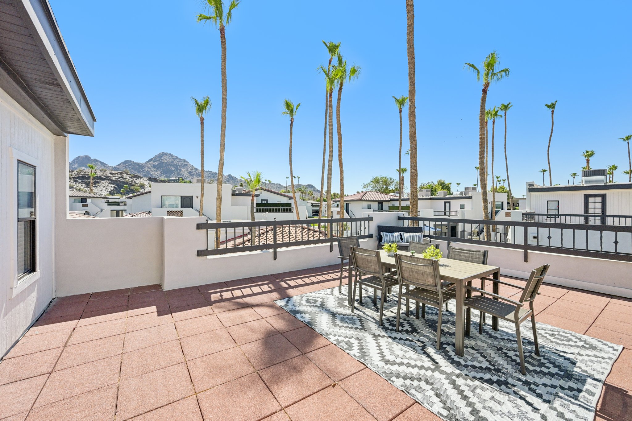Rooftop patio with a dining table and chairs, offering stunning views of the surrounding mountains and community at Views at the Peak in Phoenix, AZ.