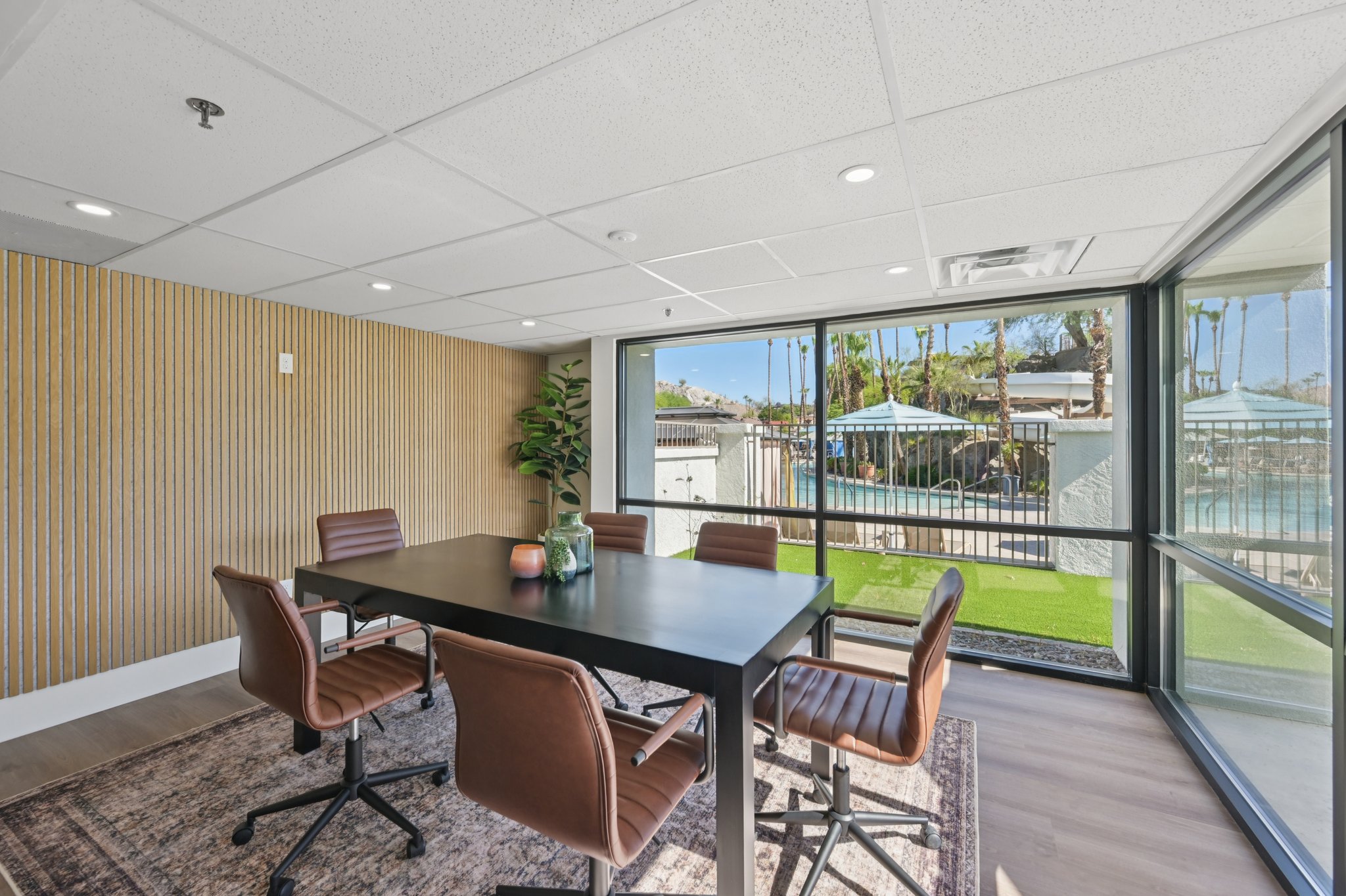 Resident co-working space with a large conference table and chairs, offering a view of the pool area at Views at the Peak in Phoenix, AZ.