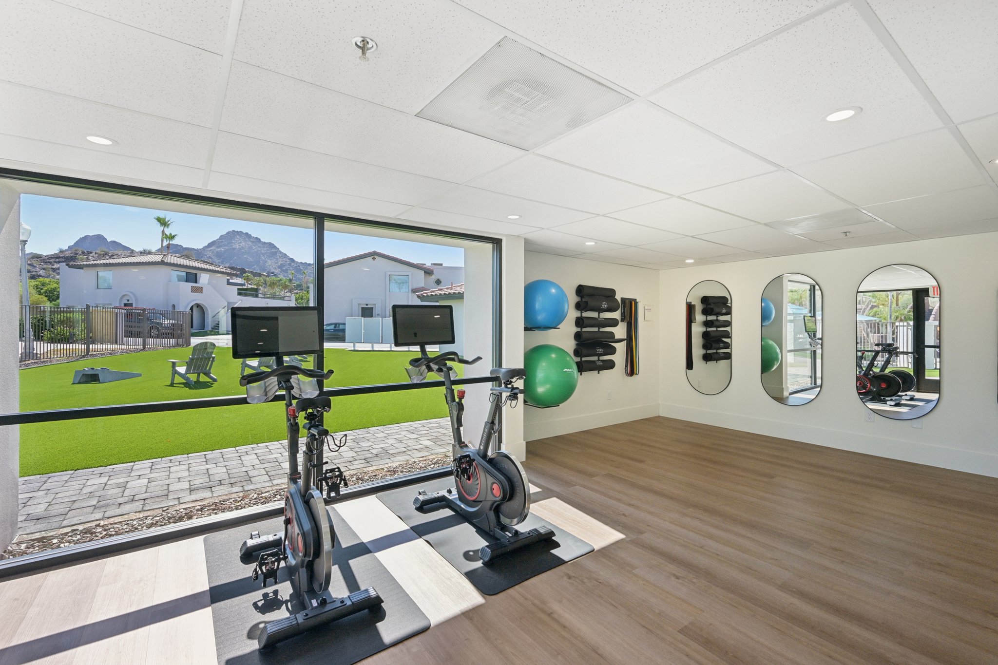 Modern resident fitness center with spinning bikes and a view of the outdoor turf area at Views at the Peak in Phoenix, AZ.