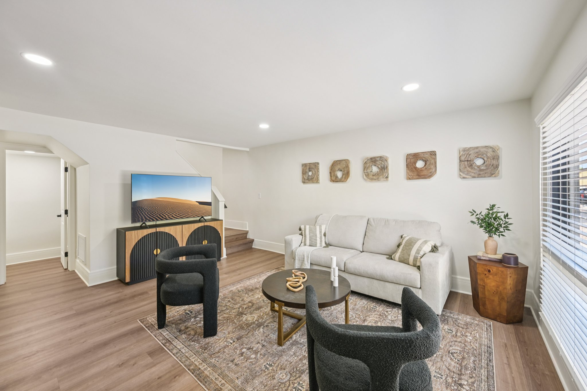 Spacious living room with a sofa, unique coffee table, and an entertainment console with a TV, in an townhome at Views at the Peak in Phoenix, AZ.