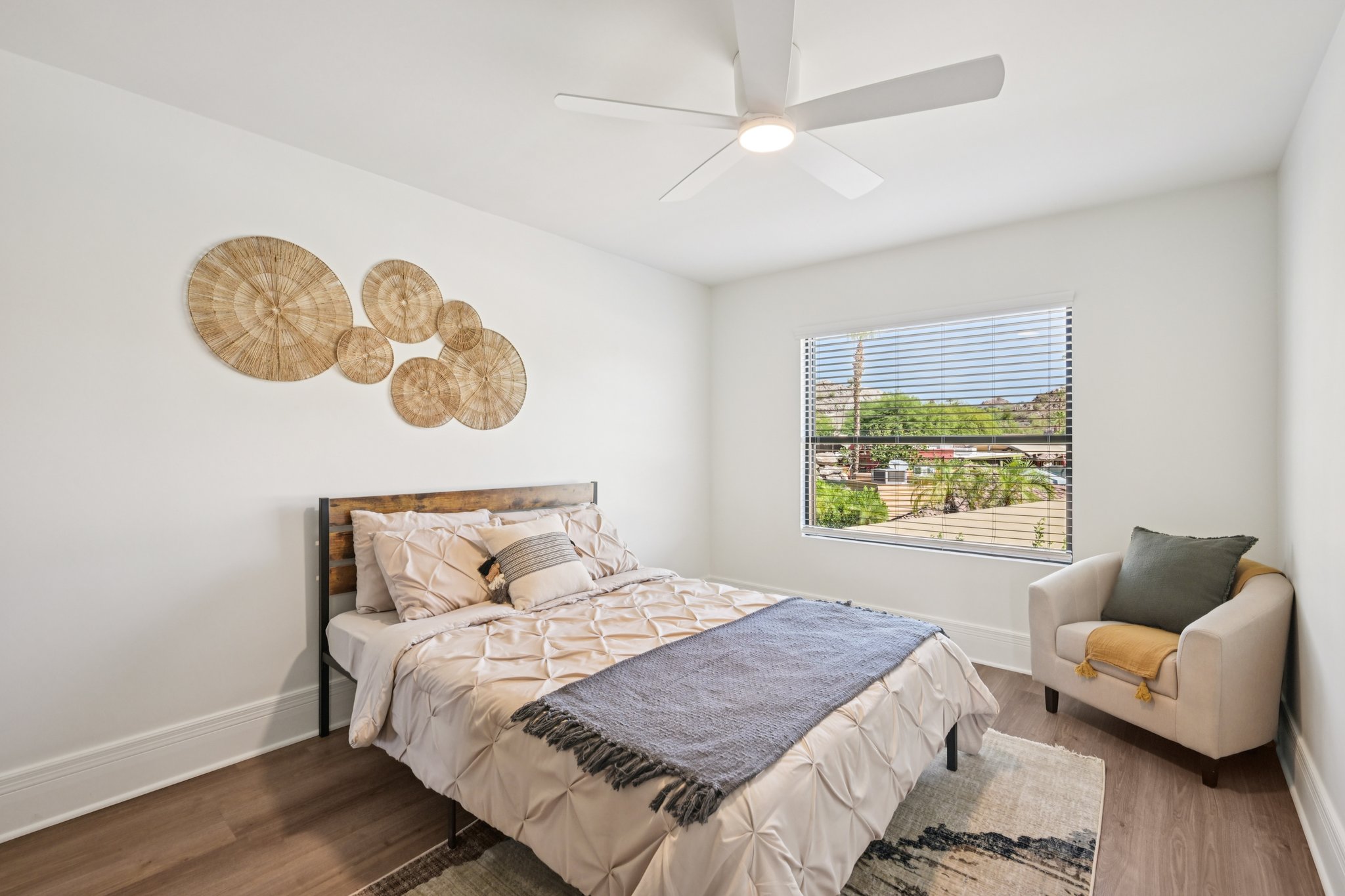 Bright bedroom with a modern bed, ceiling fan, and large windows with desert views, in a townhome at Views at the Peak in Phoenix, AZ.
