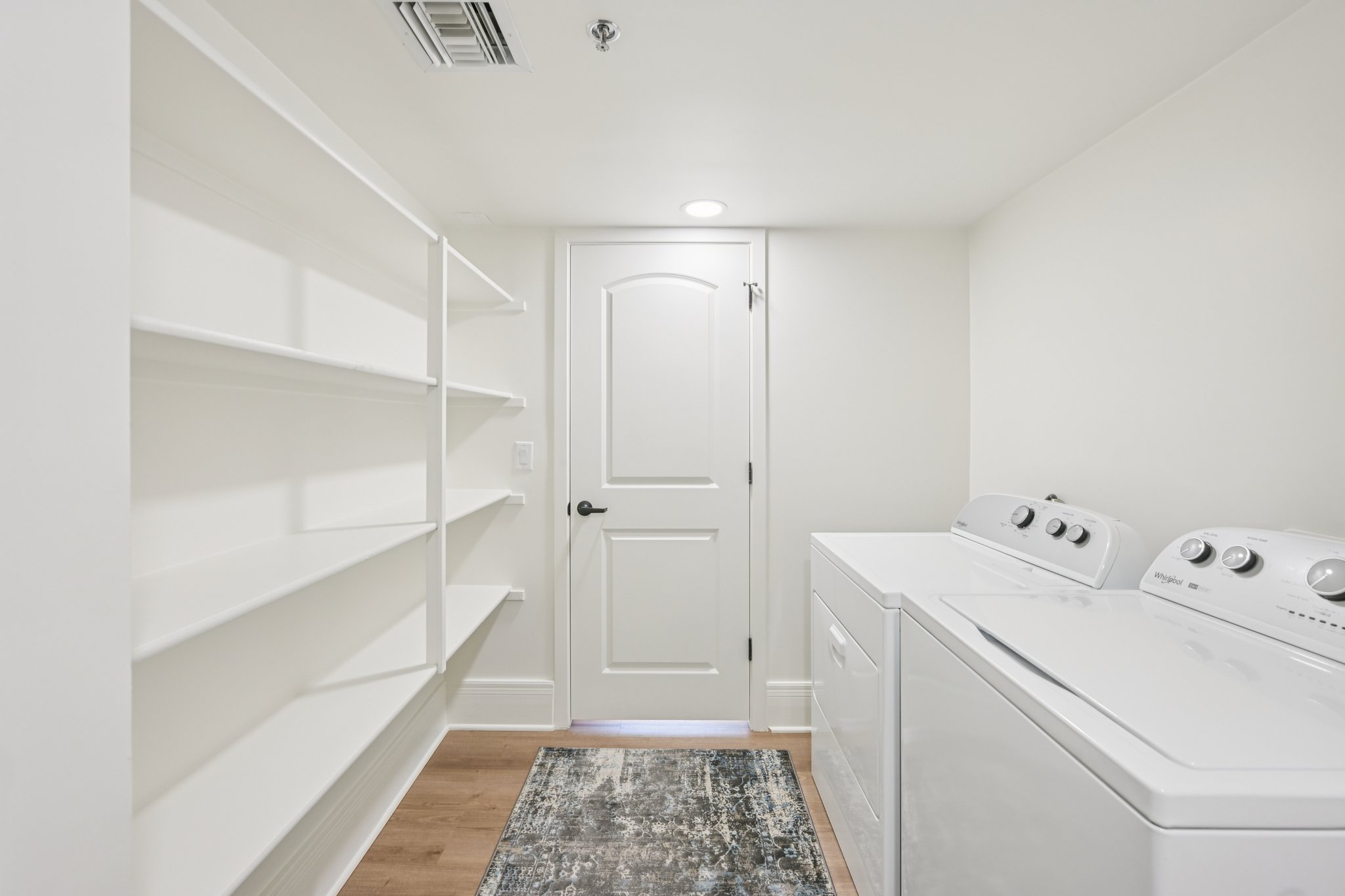 Dedicated laundry room with a white washer, dryer, and extensive shelving for storage, in a home at Views at the Peak in Phoenix, AZ.