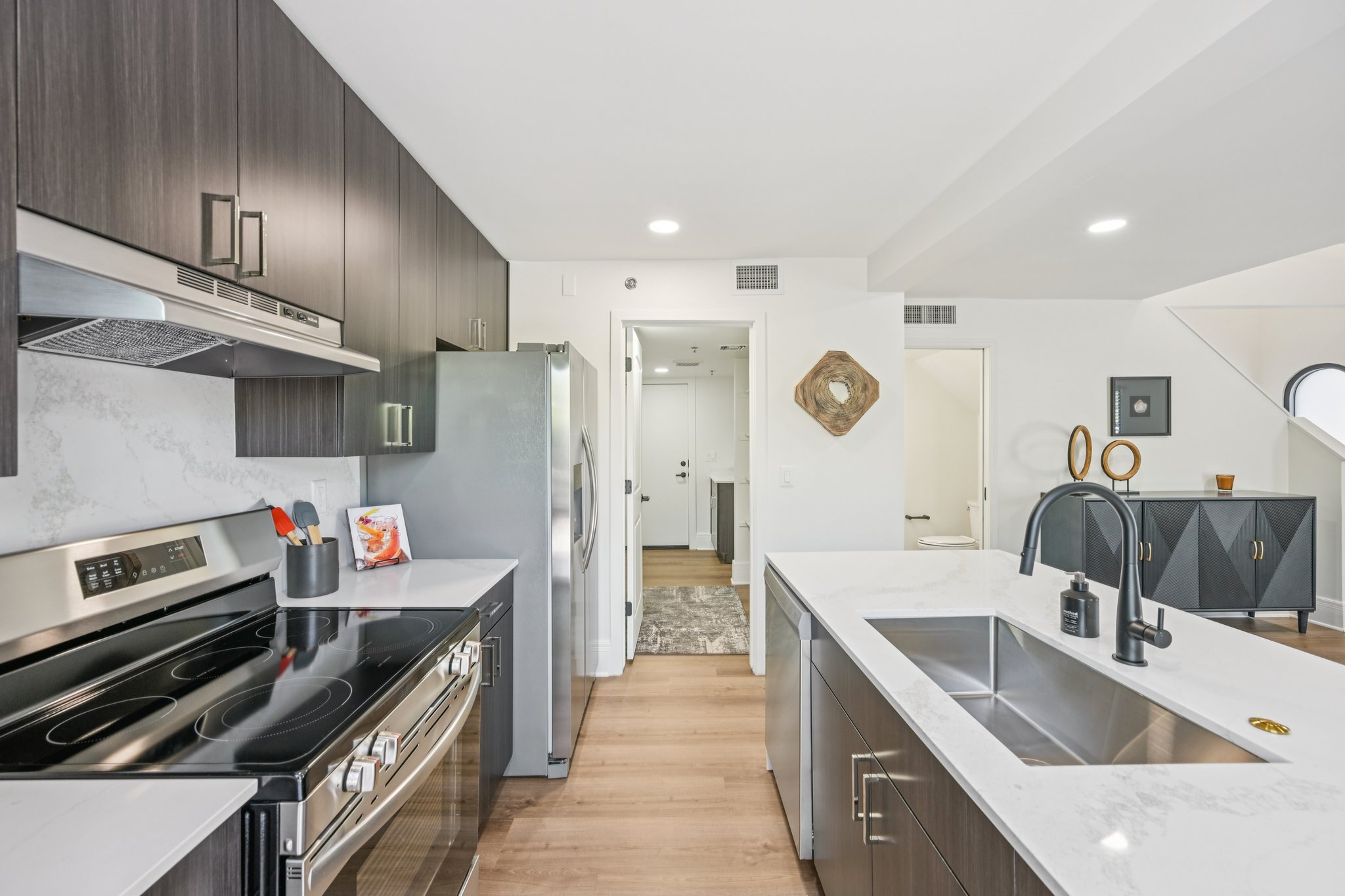 Modern kitchen with dark wood cabinets, a white island with a sink, and stainless steel appliances, in a townhome at Views at the Peak in Phoenix, AZ.