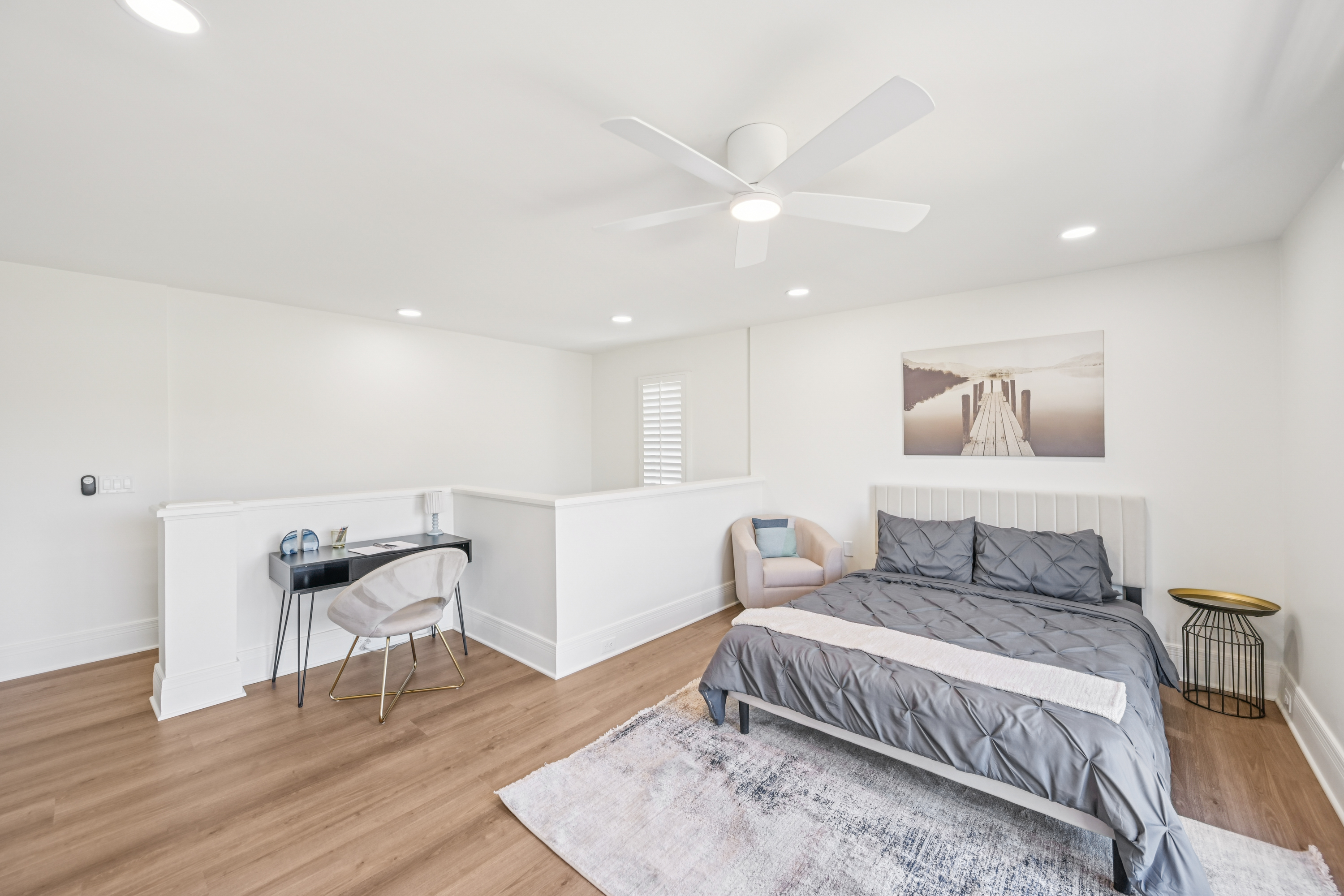Loft-style bedroom with a bed, desk, and a large window, showcasing a townhome at Views at the Peak in Phoenix, AZ.