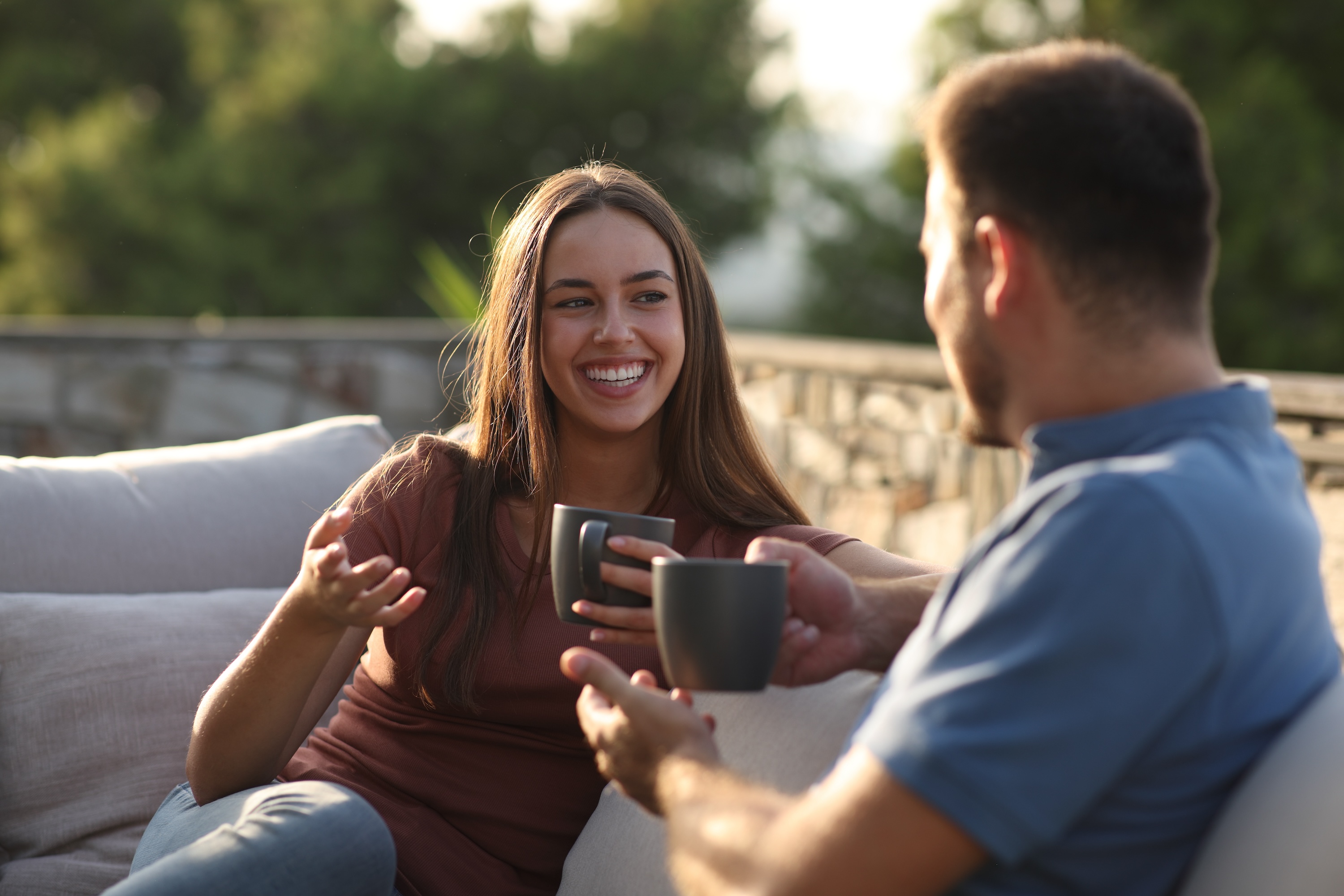 A happy couple smiling and toasting mugs on a comfortable outdoor patio, depicting a relaxing and social lifestyle at Views at the Peak in Phoenix, AZ.
