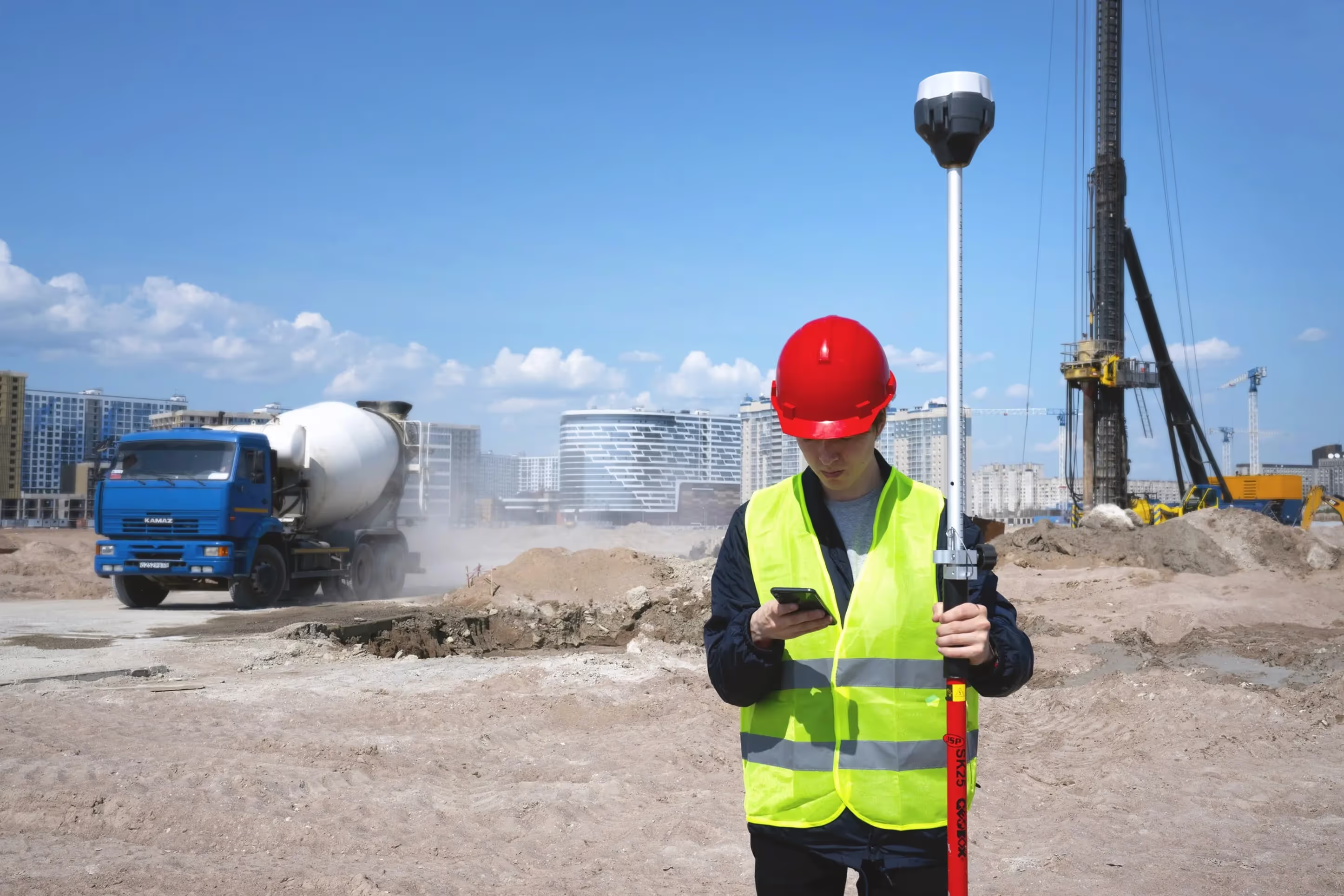Ein Mann in einer neongrünen Jacke steht mit seiner Ausrüstung auf einer Baustelle