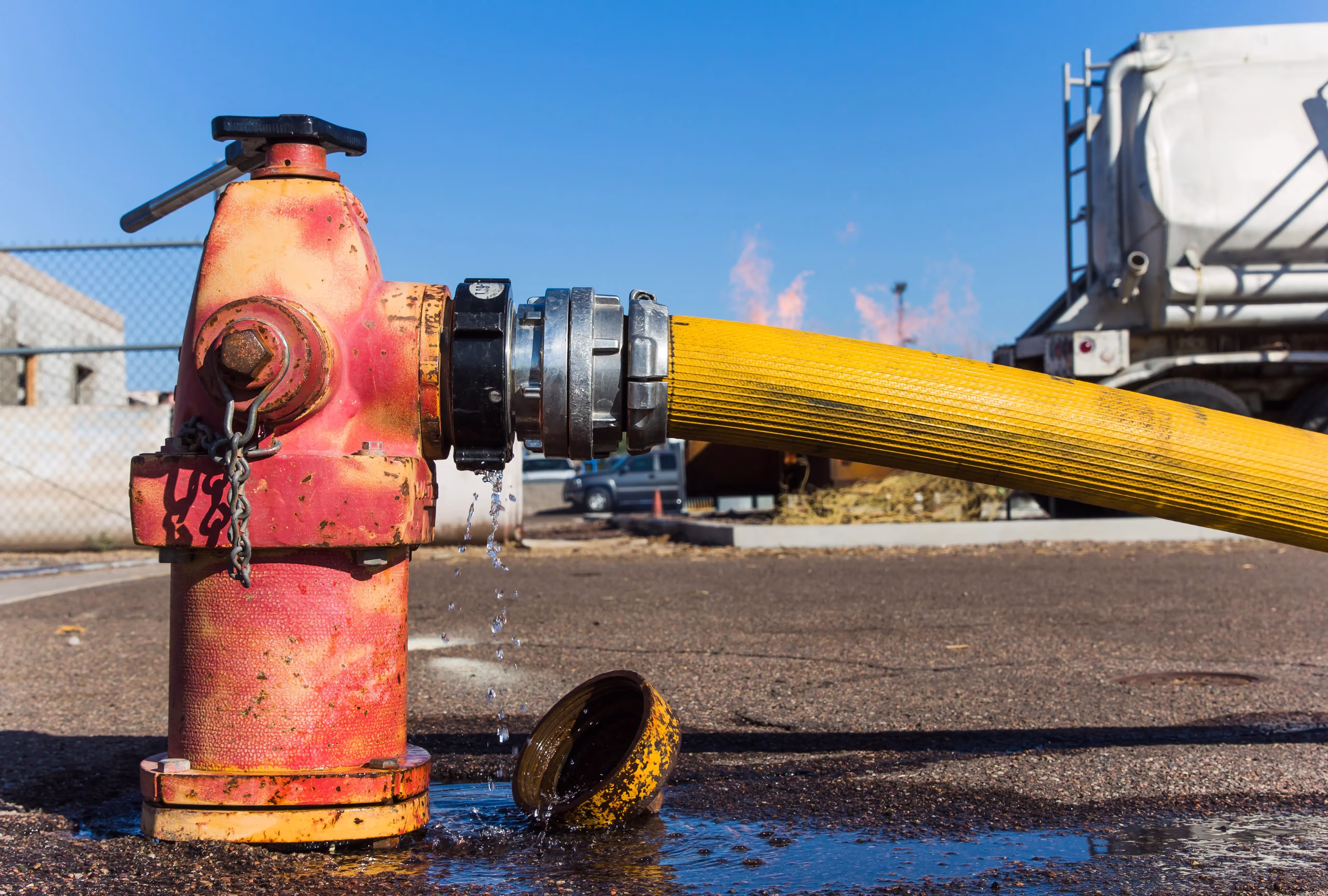 Bild eines roten Hydranten, der mit einem Wasserschlauch verbunden ist