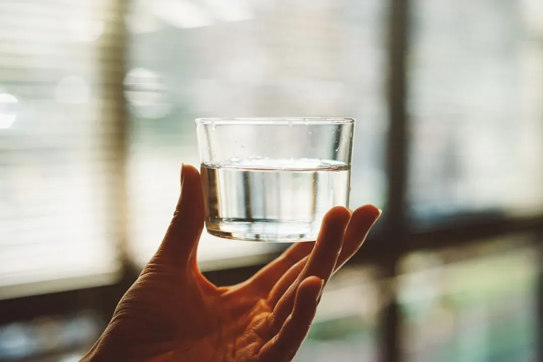 Bild einer Hand, die ein Wasserglas trägt