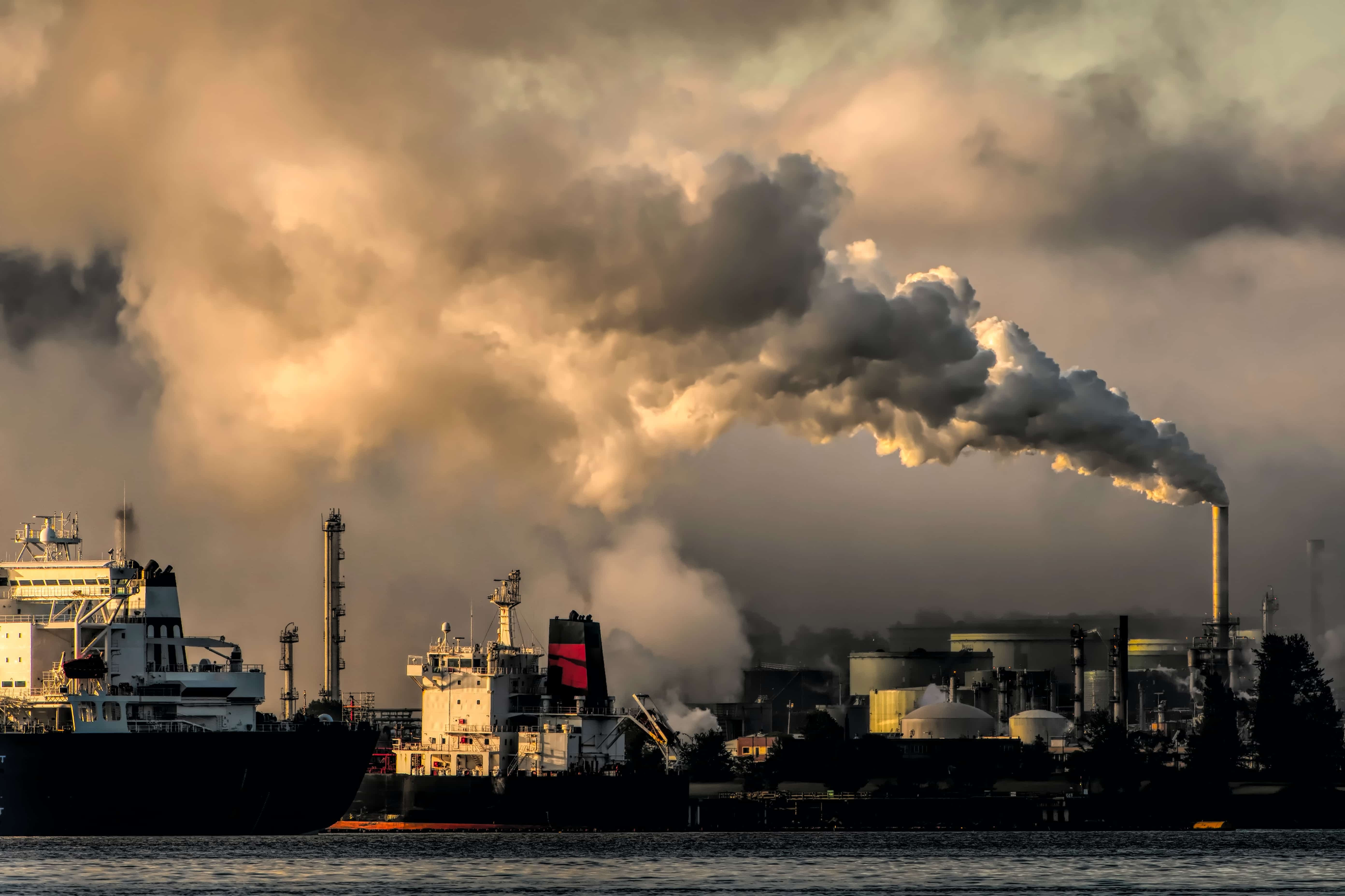 Fabrikgebäude am Wasser stößt Abgase in die Atmosphäre