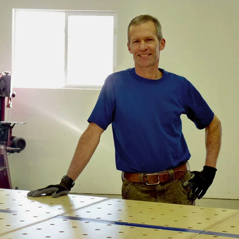 Man in a blue shirt smiling with a workbench