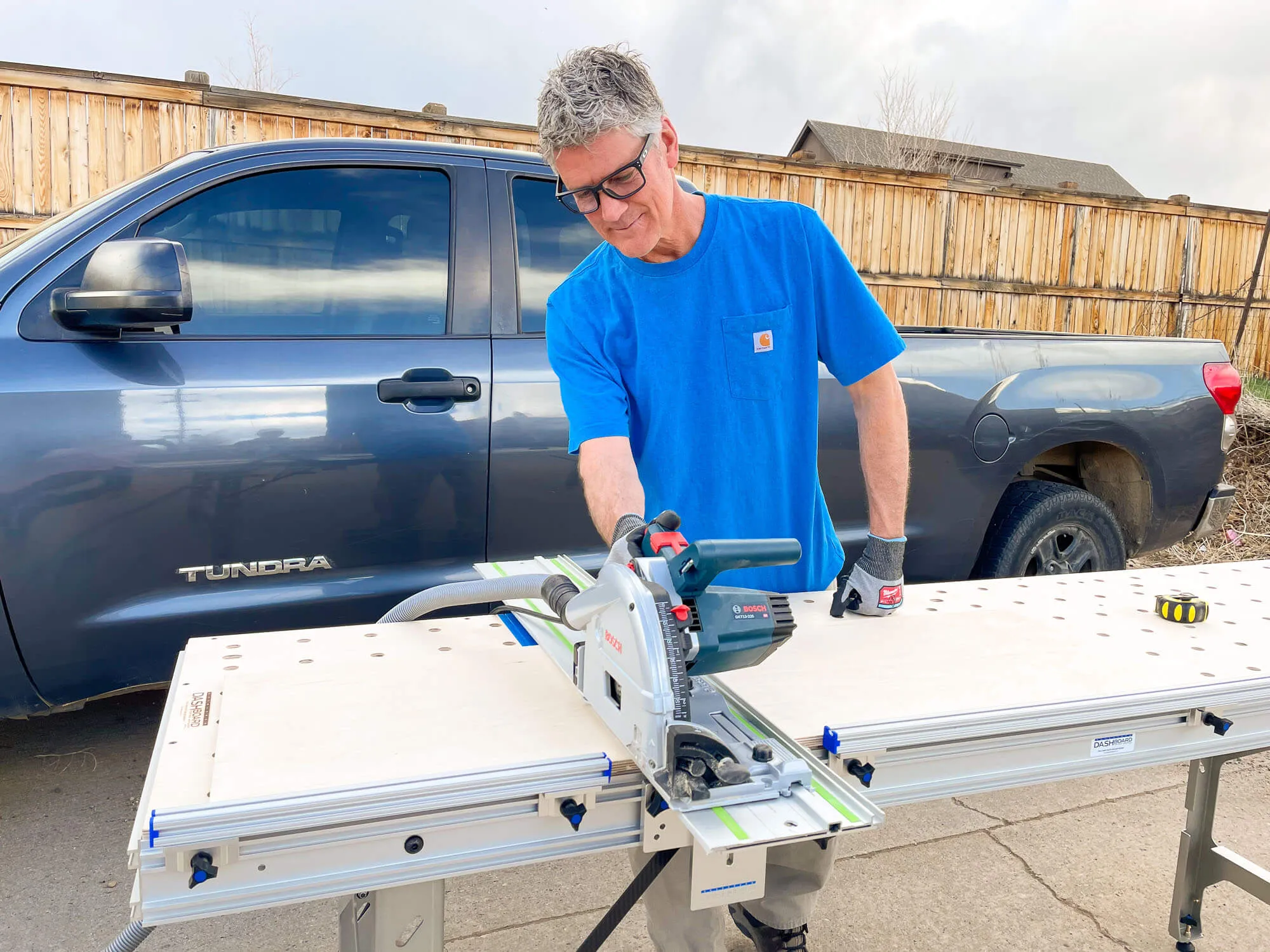 Man working on a bench using a saw across the table cutting wood