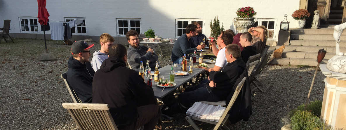 Gemeinsames Teamessen an einem langen Tisch in der Sonne
