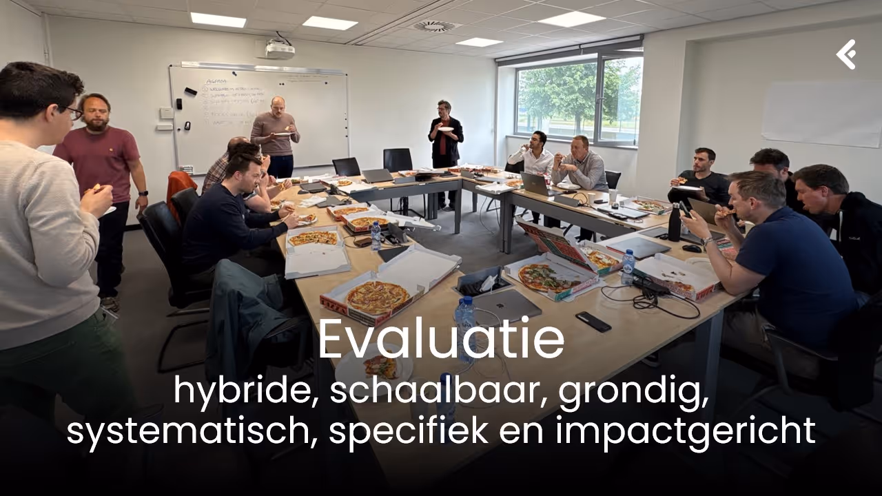 Group of people sitting and standing around a conference table eating pizza in a bright meeting room.