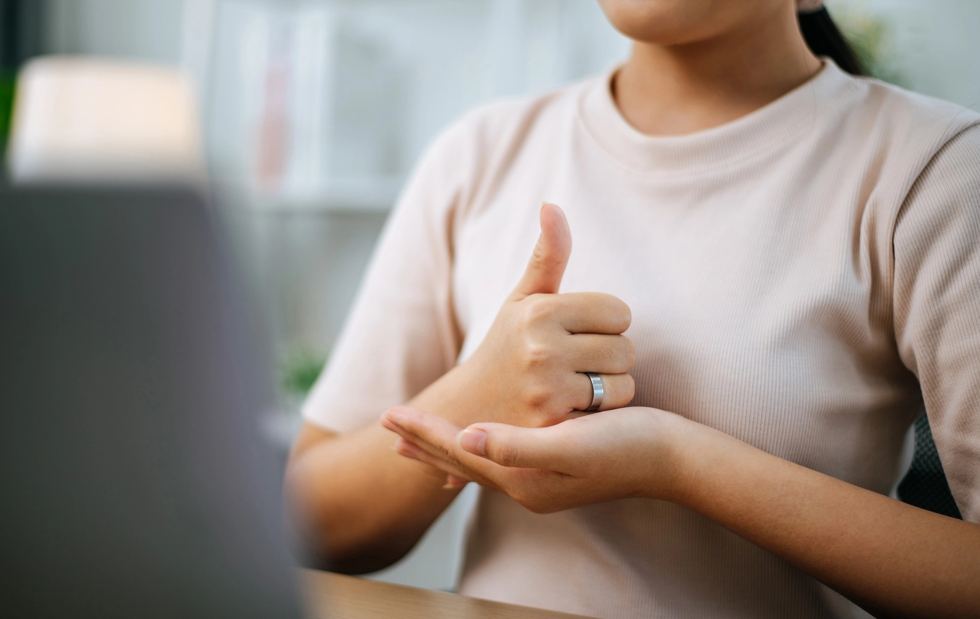 Close-up of a woman communicating in sign language online at a laptop at home