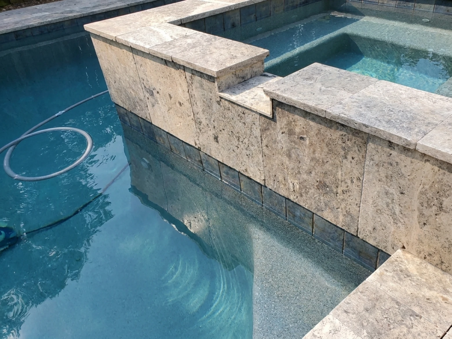 A Katy, TX homeowner testing pool water with a test kit beside a sparkling blue pool on a sunny day. Pool cleaning tools like a skimmer net, pool brush, and chemical containers are neatly arranged on the pool deck. Clean, bright, and inviting Texas backyard setting.