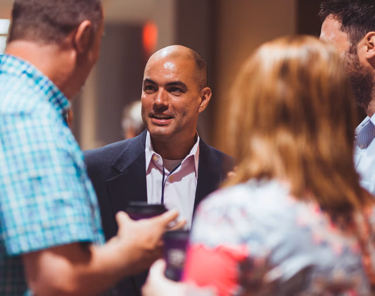Smiling professional in navy blazer conversing with colleagues at networking event