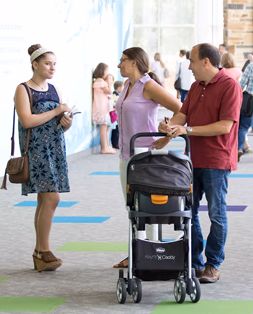 People with baby stroller conversing in bright indoor public space