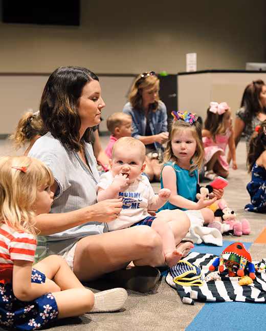 Mothers and young children sitting on floor playing with toys together