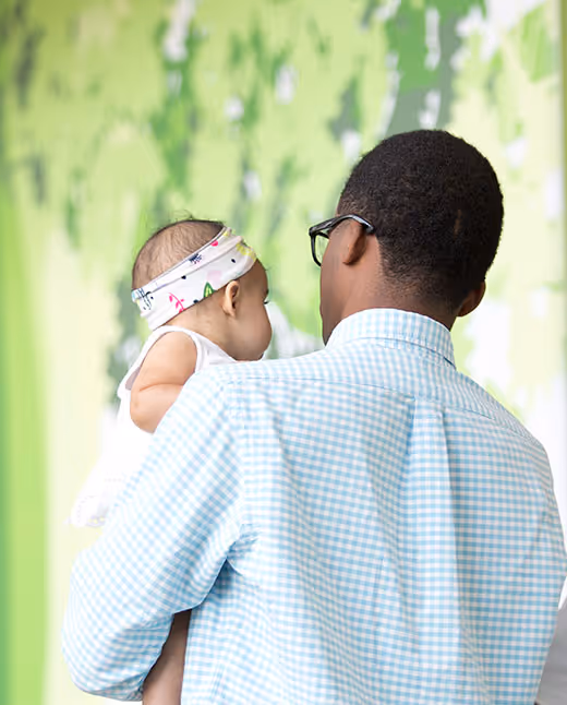 Parent holding infant with green blurred background