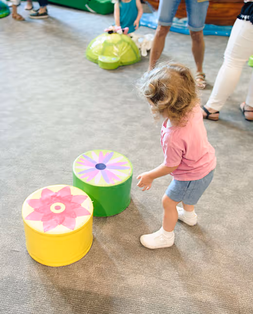 Toddler in pink shirt playing with colorful cylindrical blocks