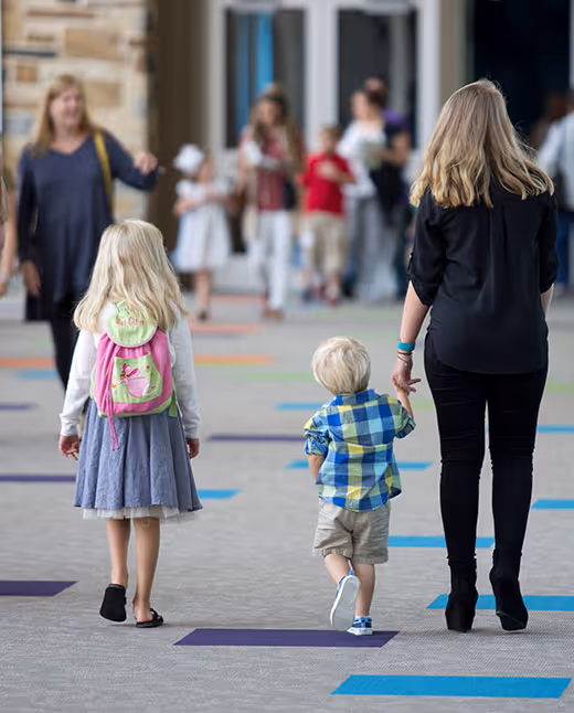Children walking with adults on colorful floor in school or community center