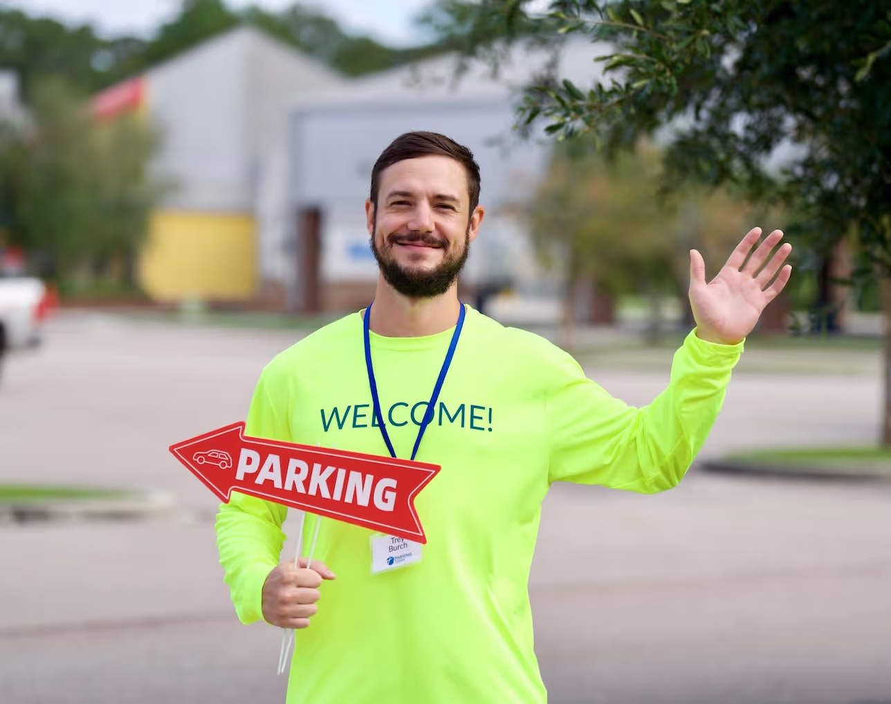 A volunteer on the parking team smiling and waving as he directs cars at First Baptist Church in Covington