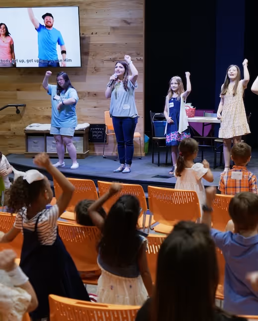 Women on stage leading energetic group performance with raised arms