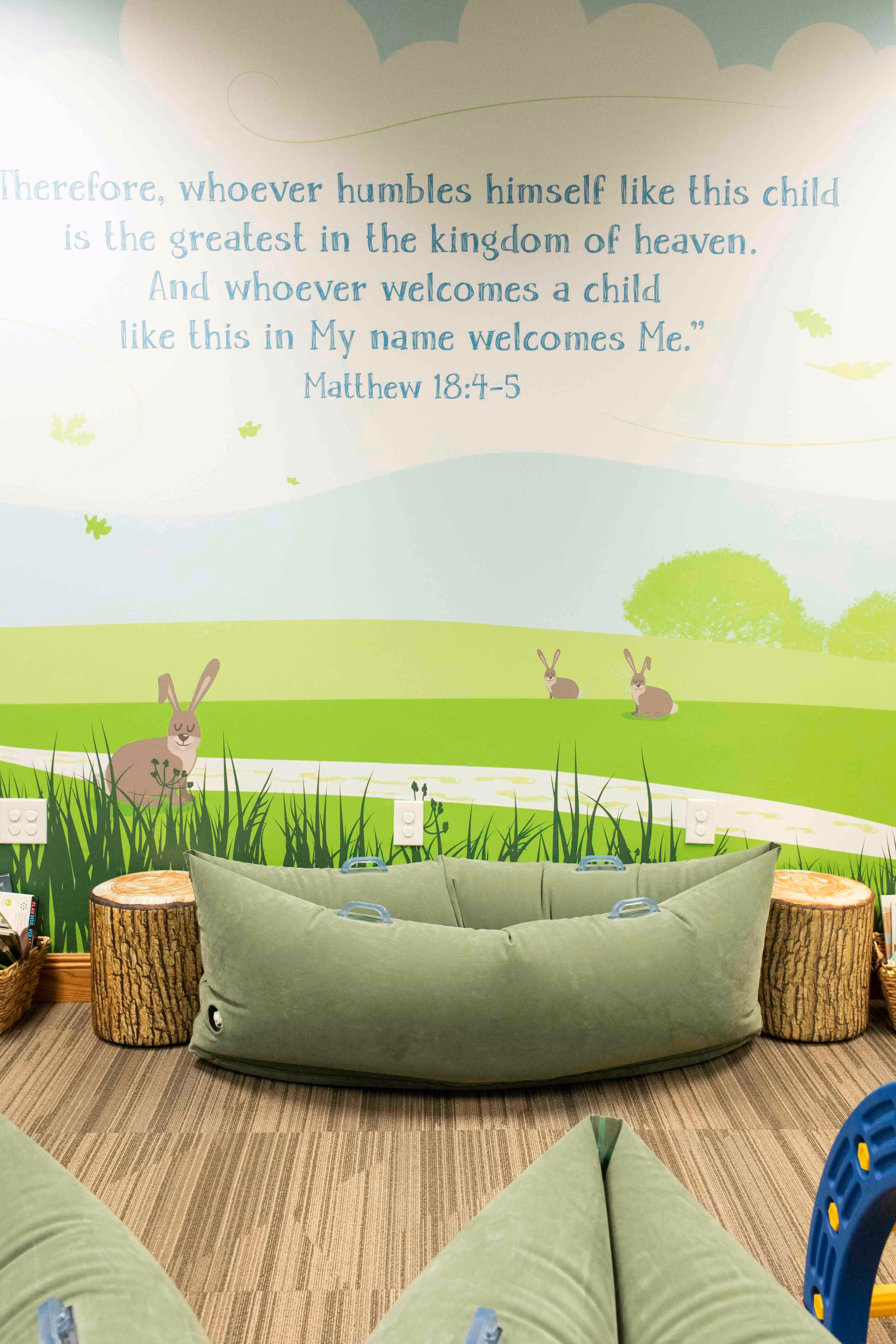 Biblical verse with bunnies, green landscape, and cozy green cushioned seating
