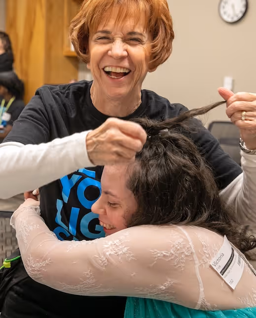 Joyful woman cutting hair of smiling person in salon chair