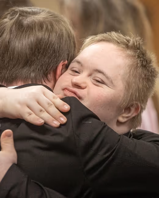 Child with Down syndrome hugging someone warmly and smiling