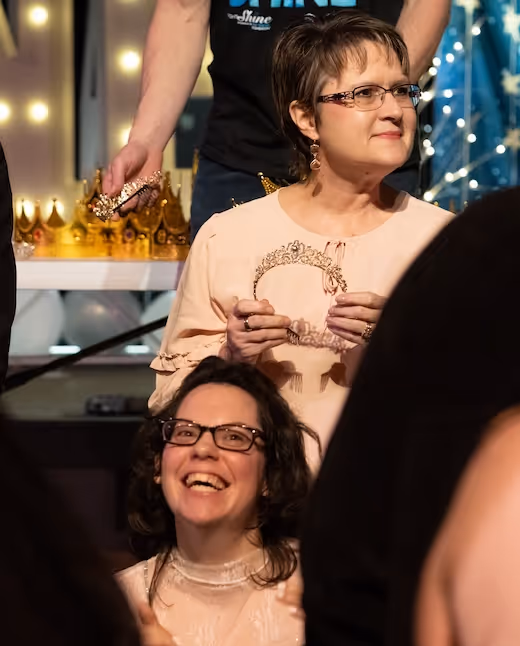 Joyful people at party with golden paper crowns and festive lights