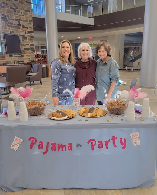 Three women hosting a cheerful pajama party event with snacks