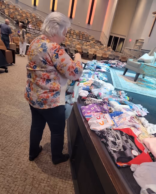 Elderly person examining colorful clothing display in auditorium