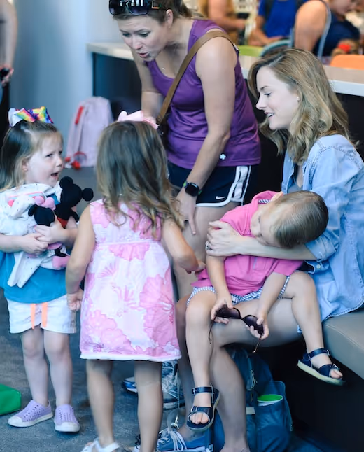 Children and women interact in a colorful, casual indoor setting