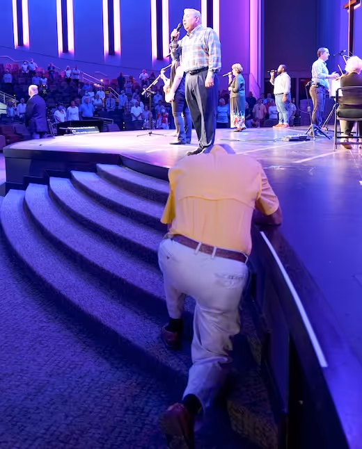 Worship band performing on stage with blue lighting and audience in background